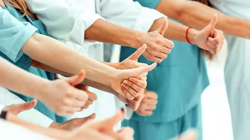 medical professionals in scrubs giving a thumbs-up